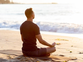 Man sitting meditating on a beach demonstrating that supplements can improve cognitive behaviour