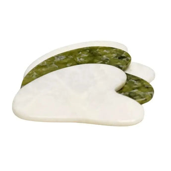Two gua sha tools displayed against a white background—one in a smooth white stone and the other in a vibrant green stone