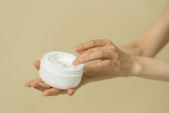 Skincare cream with hand and plain background